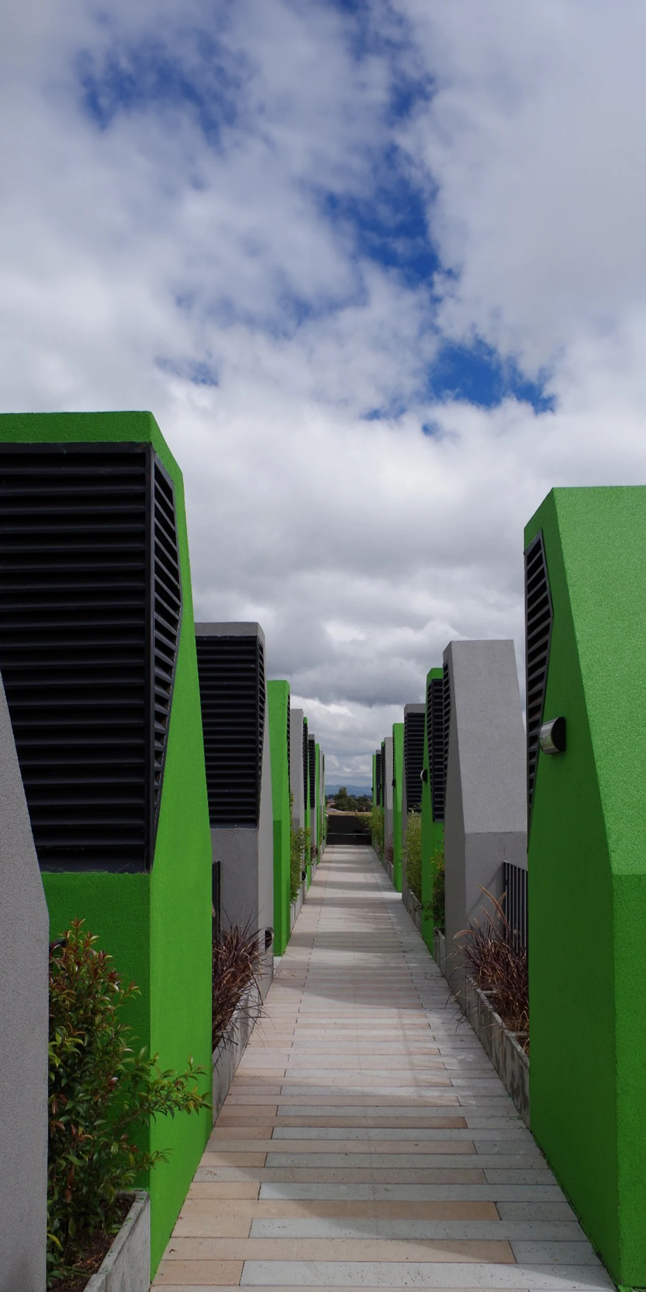 The roof is one more floor in the open air: a stone path between planters and ventilation towers, with the hills of Chía behind.