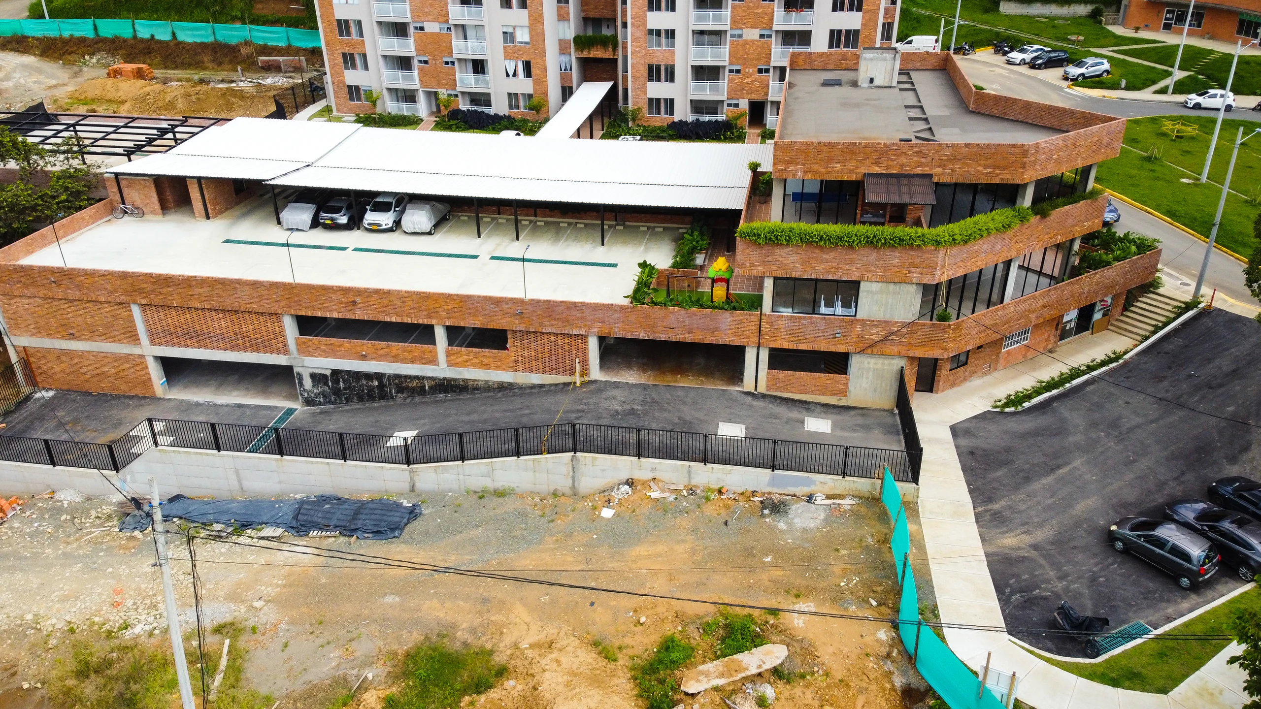 Detail of the brick plinth: half-buried parking below, trafficable roof above, and the shared planted terraces stepping with the ground.