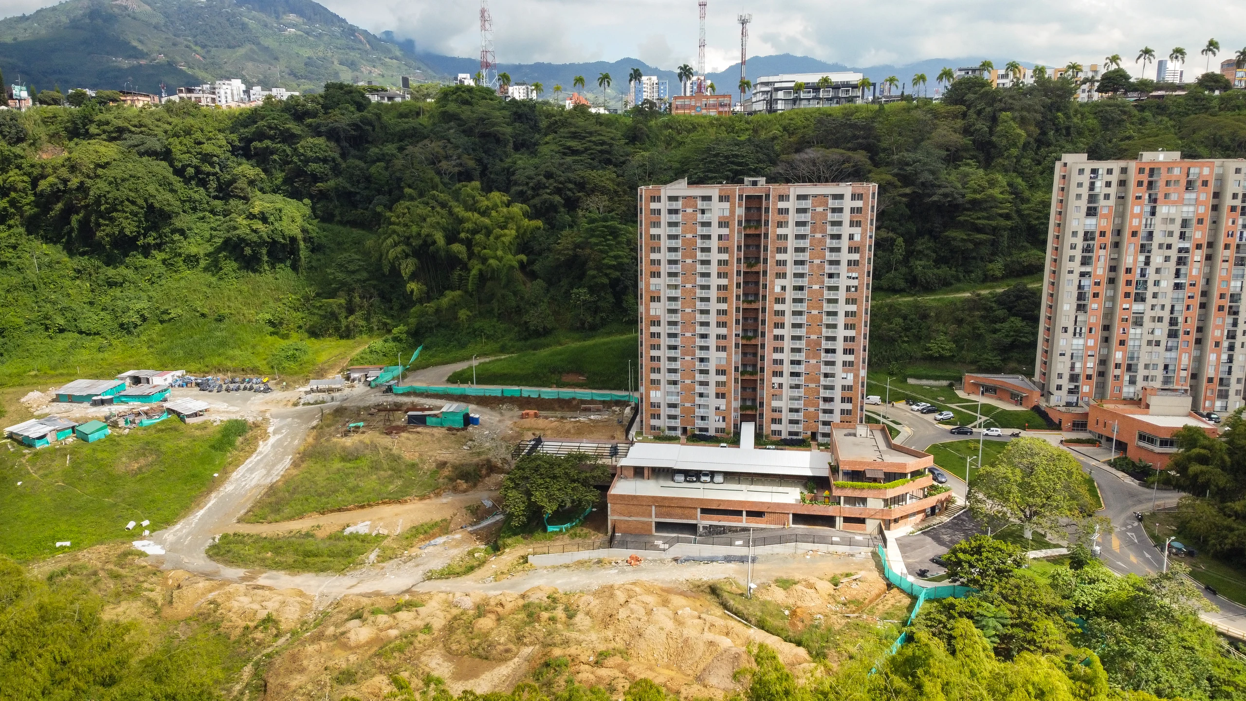 Aerial view from the west: the finished tower against the mass of the guadual, with Pereira appearing above the reserve.