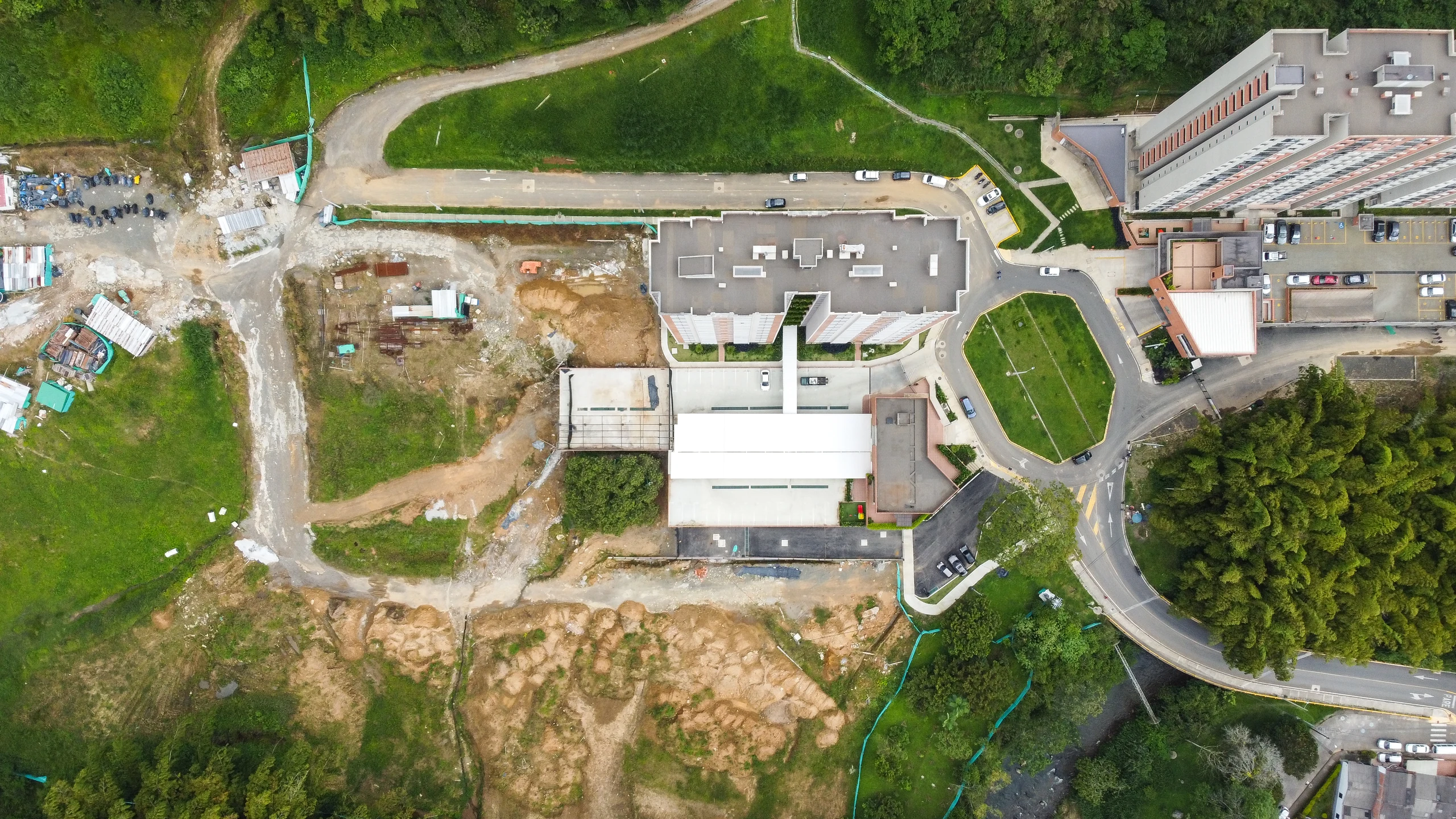 Overhead view. The platform reads as a piece of ground: it covers the parking, resolves vehicle access and gives back a usable surface on top.