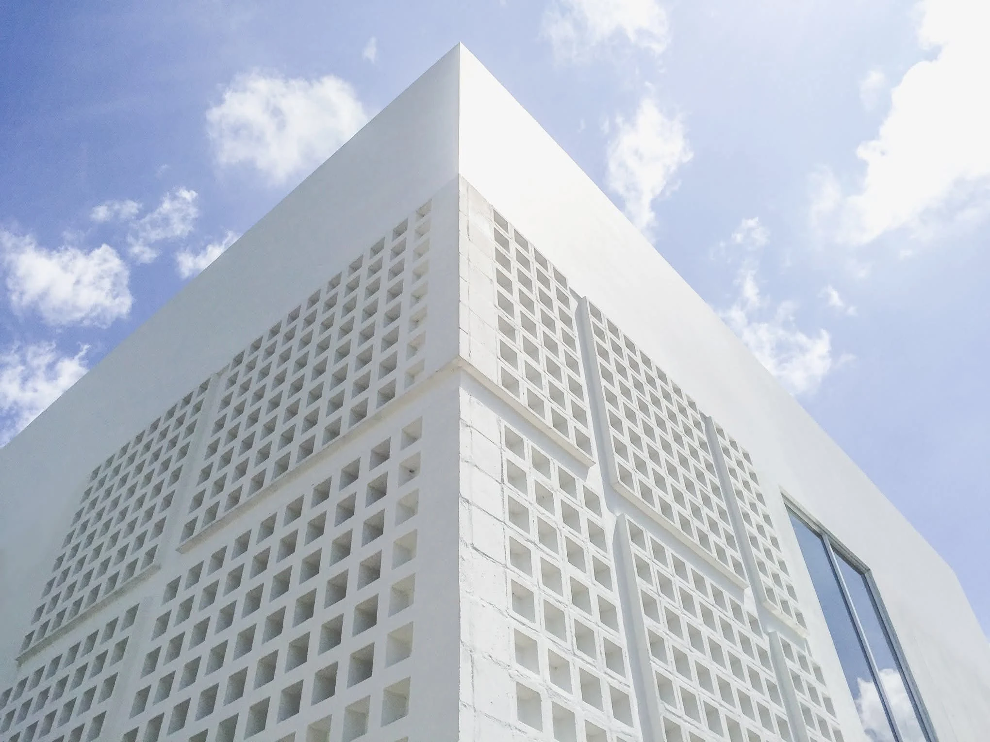 The perforated-block screen close up: a wall that shades, ventilates and lets the sky show through the openings.