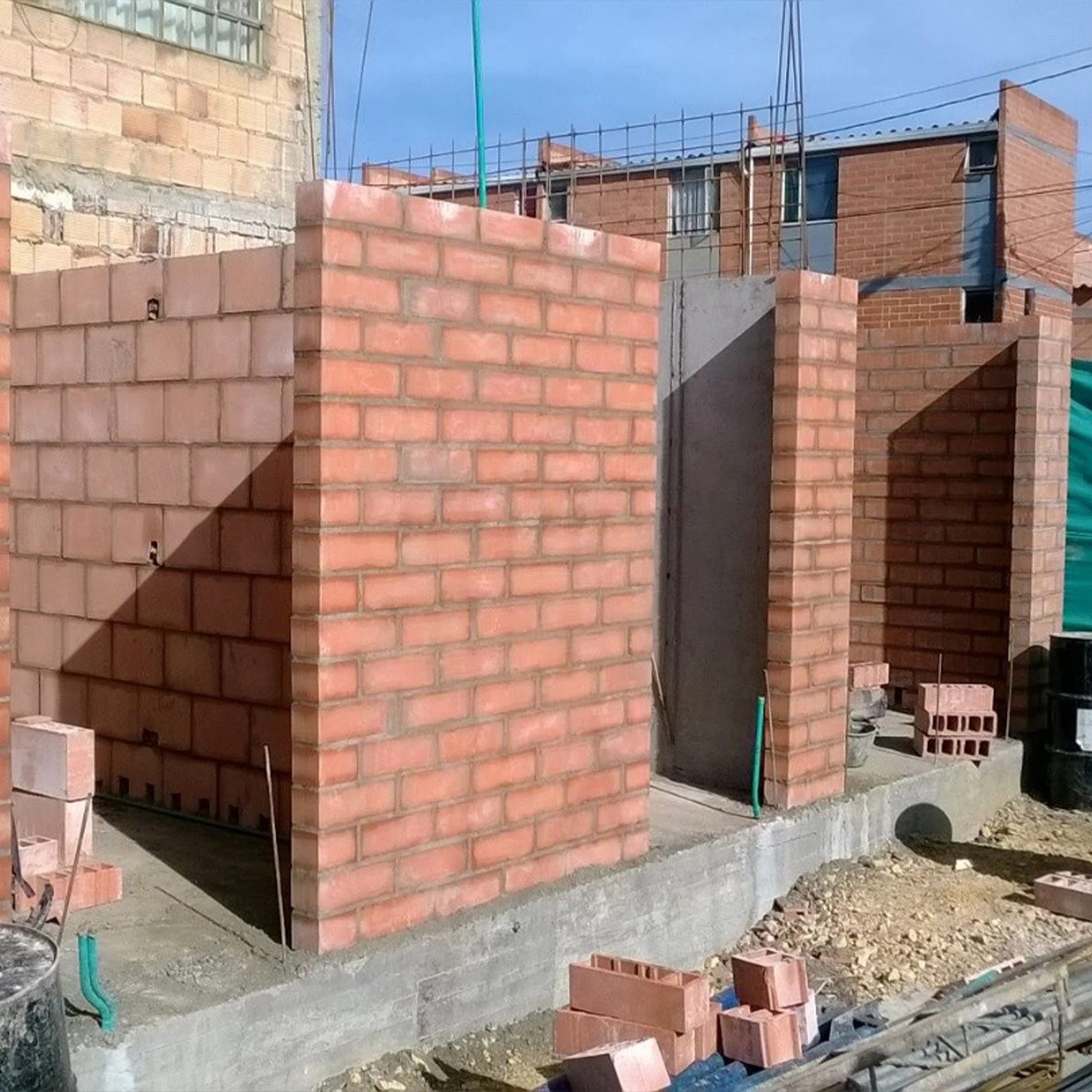 The exposed-brick walls, freshly raised, trace the openings and circulations of the homes.