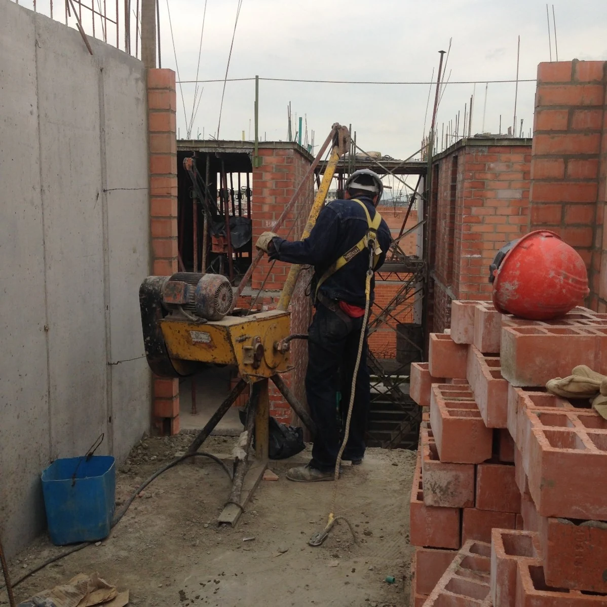 On site, the brick-by-brick detail: the exposed-brick walls and columns rise piece by piece alongside the hoisting system.