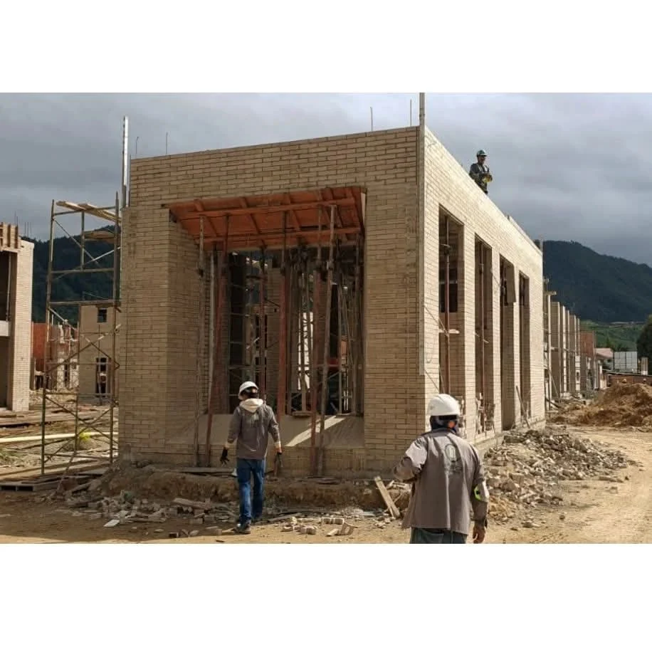 On site, the light exposed-brick volumes take shape with their vertical openings, with the Cajicá mountains in the background.