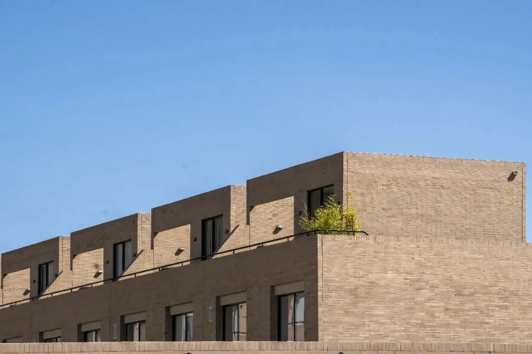 Exposed brick and large vertical openings define the restrained facade of the homes, still in structure.